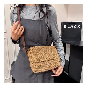 Detail of natural straw crossbody bag with brown adjustable leather strap on model