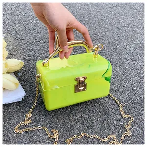 Neon green marble acrylic box bag with a golden wavy handle and chain strap detail