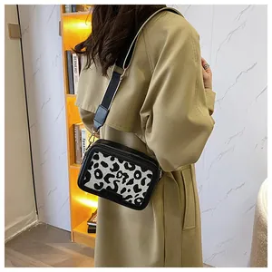 Dettaglio borsa a tracolla leopardata con ampia cinghia indossata su un trench color kaki