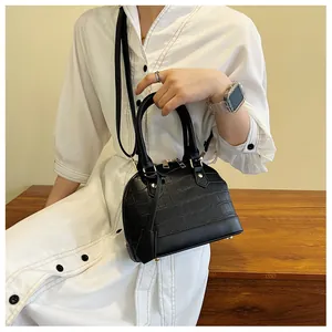 Close-up of black shell handbag with crocodile texture and light gold hardware