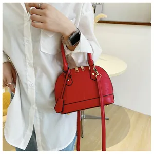 Close-up of red shell bag with crocodile texture and adjustable shoulder strap