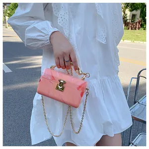 Detailed close-up of pink marble acrylic clutch bag with gold handle and metal clasp
