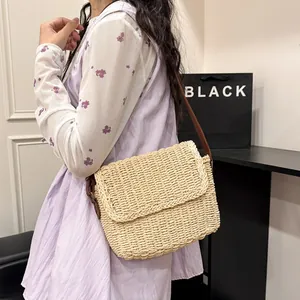 Retro straw crossbody bag in cream white with brown leather strap worn by a model