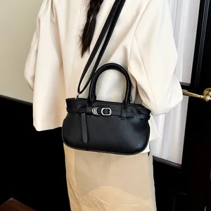 Sac à main chic noir texture litchi avec boucle argentée porté par un mannequin de côté