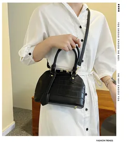 Close-up of black crocodile pattern shell bag with gold hardware and shoulder strap