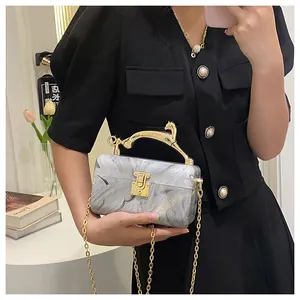 Detail of marble acrylic clutch featuring golden leopard handle and metal chain strap