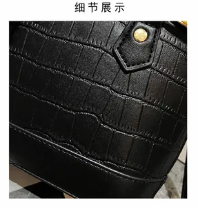 Detail of black faux leather handbag with crocodile pattern and gold metal rivet accents