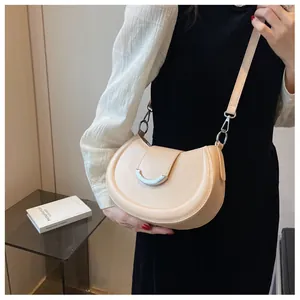 Détail du sac à bandoulière croissant beige clair avec boucle en U argentée et cuir souple