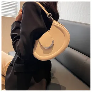 Détail du sac sous le bras en demi-lune crème avec une boucle argentée élégante