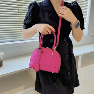 Hot pink crocodile embossed shell bag with gold hardware and a detachable shoulder strap