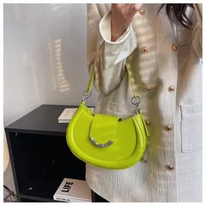 Détail du sac à bandoulière croissant vert fluo avec boucles argentées sur veste