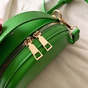 Détail du sac bandoulière rond vert avec double fermeture éclair dorée brillante