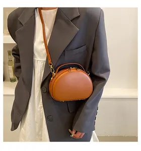 Gros plan d'un sac à main semi-circulaire en cuir marron avec crochets dorés et zip double