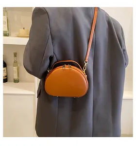 Sac bandoulière en cuir marron sur mannequin avec bandoulière réglable et zips dorés