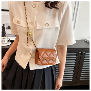 Mini sac bandoulière matelassé marron avec chaîne à bille dorée réglable porté par un mannequin
