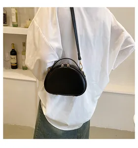 Détail du sac à main croissant en similicuir noir avec pieds métalliques et fermeture