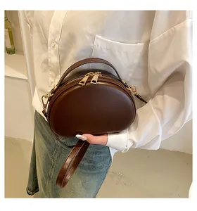 Détail du sac à main ovale marron vintage avec double fermeture éclair dorée et cuir lisse