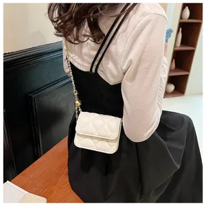 Détail du mini sac bandoulière matelassé beige avec sa fine chaîne dorée sur l'épaule