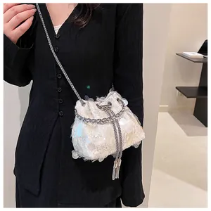Detail of off-white sequin bucket bag featuring metallic drawstring and tassel fringe