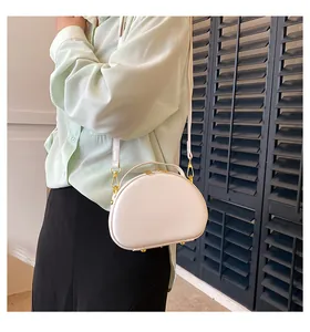 Détail d'un sac à main blanc semi-circulaire avec ferrures dorées et texture lisse