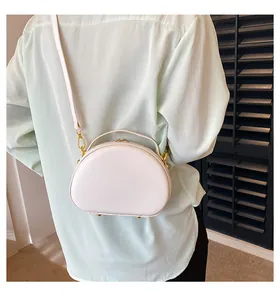 Détail d'un sac à main blanc semi-circulaire en cuir avec ferrures dorées élégantes