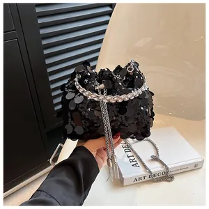 Detail of black sequined bucket bag with rhinestone handle and metallic fringe tassels