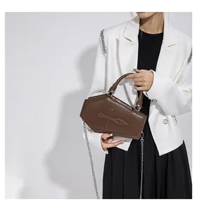 Close-up of gothic coffin-shaped crossbody bag with metallic cross detail and silver chain