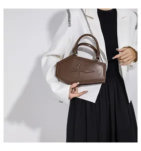 Detailed view of brown coffin-shaped crossbody bag with gothic cross and chain strap