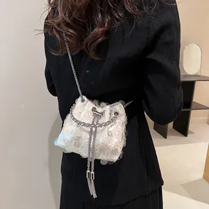 Sparkly white sequin bucket bag with metal chain strap and fringe tassel on black dress