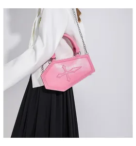 Pink coffin-shaped crossbody bag featuring a 3D cross detail and silver chain strap