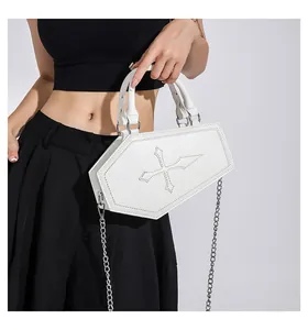 Detail of white coffin shaped purse with large cross stitching and silver chain strap