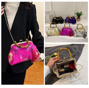 Détail du sac vintage avec poignée en bambou, broderie florale et gland en métal