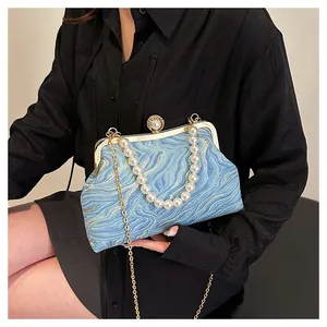 Détail du sac bleu avec broderie ondulée et poignée en perles volumineuses