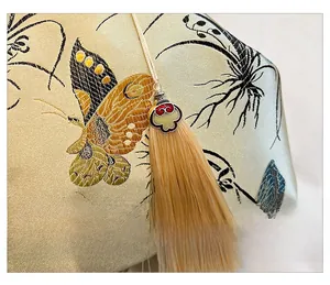 Détail de la broderie papillon et du pompon sur un sac à chaîne en forme de coquille