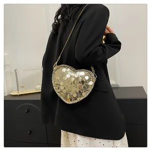 Detail of heart-shaped crossbody bag featuring shimmering gold sequins and chain strap