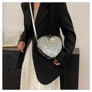 Silver sequin heart-shaped crossbody bag shown on model for style and scale
