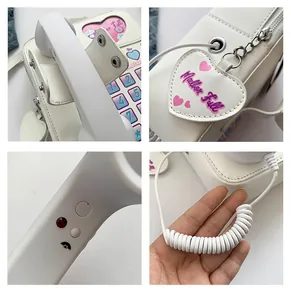 Détail du sac téléphone rétro montrant le cadran le charme cœur et le combiné blanc