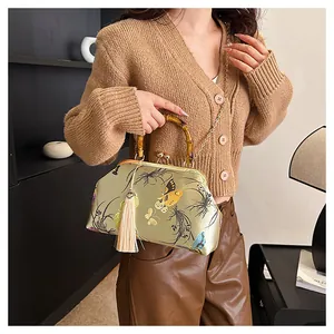 Détail du sac brodé vintage avec poignée en bambou et décoration de pompon en soie