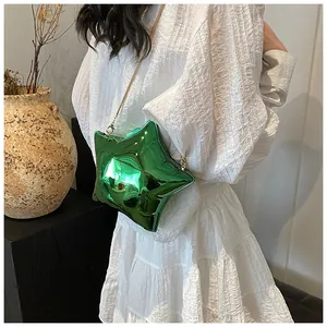Star-shaped metallic green crossbody bag with gold chain strap on a white dress