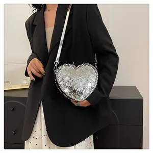 Detail of silver sequin heart-shaped crossbody bag with metallic leather strap on model