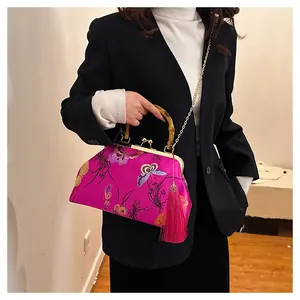 Détail du sac rouge rose avec broderie florale de papillon et poignée en bambou naturel
