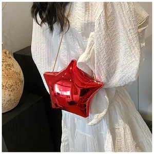 Detail of red star-shaped metallic bag with golden chain strap on a white dress