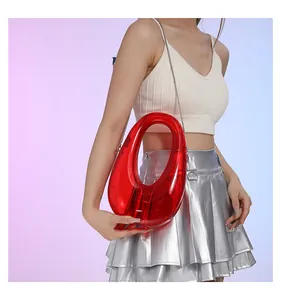 Detalle de bolso rojo transparente de acrílico con asa ovalada y cadena plateada