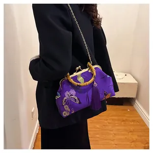 Détail du sac brodé violet avec motif papillon, poignée en bambou et gland en soie