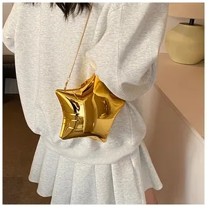 Detail view of metallic gold star-shaped crossbody bag with slim chain on a model