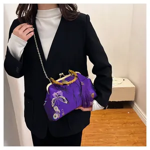 Détail du sac en soie violette avec poignée en bambou et broderie papillon élégante