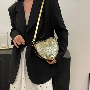 Fashion heart shaped sequin crossbody bag in gold worn over a stylish black blazer suit