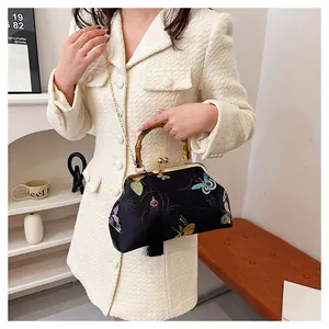Détail d'un sac coquillage vintage avec broderie papillon et poignée en bambou