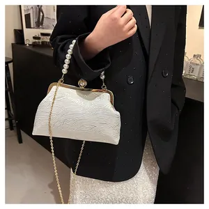 Détail du sac coquillage blanc avec poignée en perles et chaîne dorée