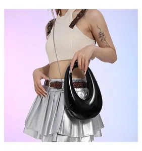 Bolso ovalado negro brillante con cadena plateada sobre fondo de degradado suave
